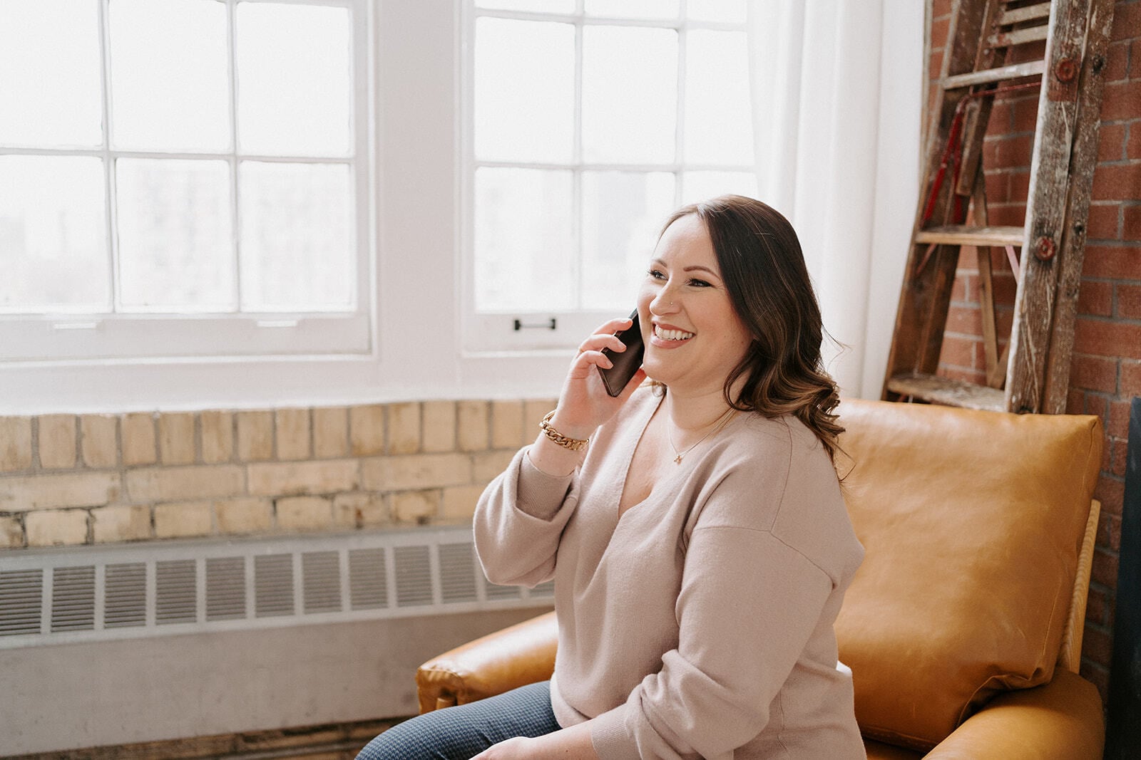 Woman talking on a mobile phone while seated in front of a window.